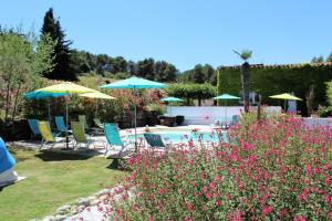 a garden with chairs and umbrellas and a swimming pool at Gîte Carcassonne le Relais de la Cavayere in Carcassonne +17 photos