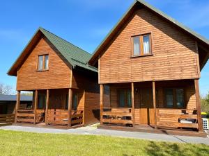 een groot houten huis met een groen dak bij Hostel Przystan in Rościno