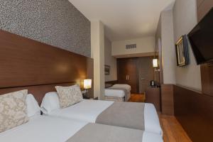 バルセロナにあるバルセロナ ホテル コロニアルのベッド2台とテレビが備わるホテルルームです。