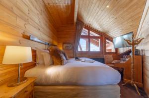 ラルプ・デュエズにあるHôtel Au Chamois d'Or by Les Etincellesの木製キャビン内のベッドルーム1室(大きな白いベッド1台付)