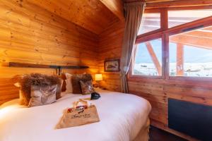 ein Schlafzimmer mit einem Bett in einer Holzhütte in der Unterkunft Hôtel Au Chamois d'Or by Les Etincelles in L'Alpe-d'Huez
