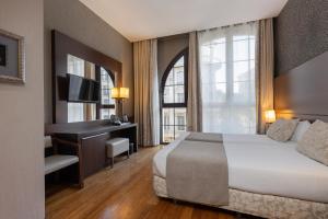 um quarto de hotel com uma cama, uma secretária e uma janela em Barcelona Hotel Colonial em Barcelona