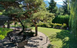 un parc avec des bancs, des tables et des arbres dans l'établissement Logis Hotel-Restaurant Spa Le Lac, à Embrun