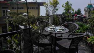 d'une table de patio et de chaises sur un balcon orné de plantes. dans l'établissement Hotel Broadway Mall Road Darjeeling - Family Joy Vacations & Best Location, à Darjeeling