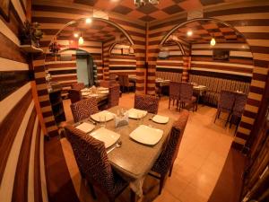 Hotel Broadway Mall Road Darjeeling - Family Joy Vacations & Best Location في دارجيلنغ: مطعم مع طاولة وكراسي في غرفة