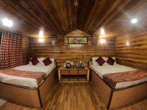 una camera con 2 letti in una baita di tronchi di Hotel Broadway Mall Road Darjeeling - Family Joy Vacations & Best Location a Darjeeling