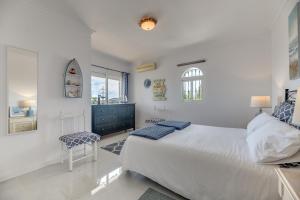 a white bedroom with a bed and a chair at Casa Panoramica in Mijas +22 photos