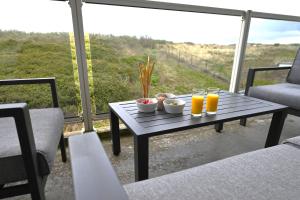 een tafel met 2 glazen sinaasappelsap op een balkon bij Fika - Résidence Deurloo 55-10 in Cadzand