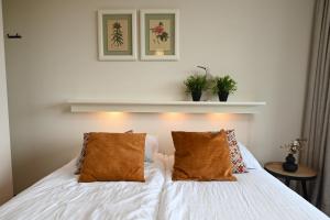 een slaapkamer met een wit bed met 2 kussens bij Fika - Résidence Deurloo 55-10 in Cadzand