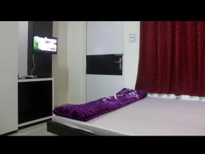 Bett in einem Zimmer mit einem roten Vorhang in der Unterkunft Hotel Srimanta sankardev in Majuli