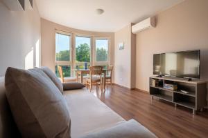 a living room with a couch and a flat screen tv at Moana Sunset Apartment in Ahtopol