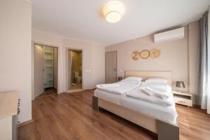 a white bedroom with a large bed and wooden floors at Moana Sunset Apartment in Ahtopol