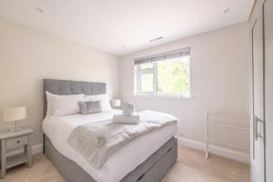a white bedroom with a large bed and a window at Windsor Charm Spacious 3-Bed, Parking & Garden - By Tempstay in Windsor