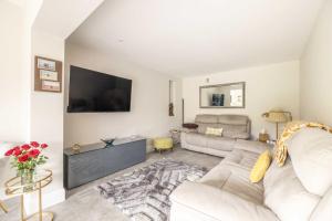 a living room with a couch and a tv at Windsor Charm Spacious 3-Bed, Parking & Garden - By Tempstay in Windsor