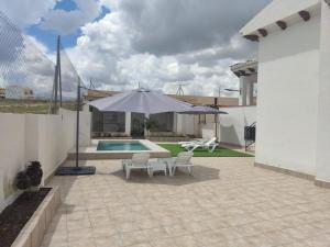 un patio con sombrilla, sillas y piscina en El rincón de la buena vista en Las Gabias
