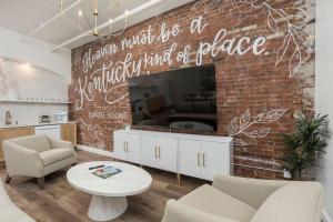 a living room with a brick wall with a tv at Fancy Heart of Kentucky Suite in Louisville