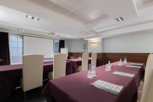 una sala de conferencias con mesas púrpuras y sillas blancas en Barcelona Hotel Colonial, en Barcelona