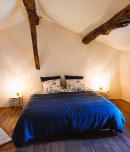 una camera da letto con un letto con lenzuola blu e due lampade di Clos Baroanni - Studio La Volière a Terraube
