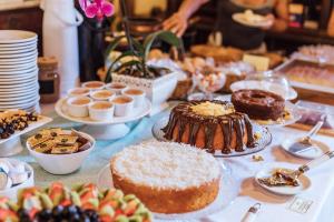 a table topped with cakes and other desserts on plates at Pousada Terra Madre in Ilhabela