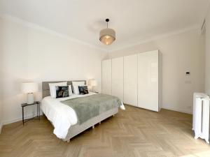um quarto branco com uma cama grande e pisos em madeira em 3 pièces rénové Limitrophe Monaco em Beausoleil