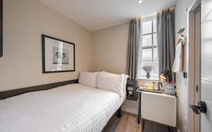 een kleine slaapkamer met een bed en een raam bij King's Cross Express Inn in Londen