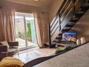 a living room with a tv and a staircase at New, unique, tiny house with garden in Wigston Magna