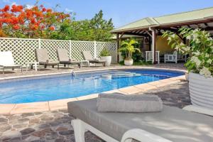 a swimming pool with chairs and a table next to it at La Source Guest House in Orient Bay