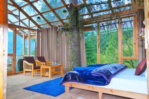 um quarto com uma cama e uma grande janela em Stargazing Treehouse Himachal em Sainj