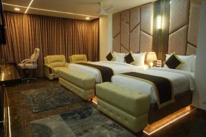 a hotel room with two beds and a sitting area at Hotel Y Palace in Ongole