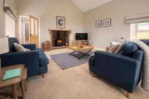 een woonkamer met 2 blauwe stoelen en een open haard bij The Rushes in Bamburgh