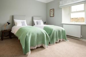 twee bedden met groene dekens in een slaapkamer bij The Rushes in Bamburgh