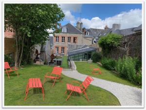 a group of red chairs and tables in a yard at Villa Dei 15 pers jacuzzi, baby-foot, 30 min mer in Villedieu-les-Poëles