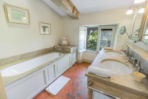 La salle de bains est pourvue de 2 lavabos, d'une baignoire et d'une fenêtre. dans l'établissement Château Mentone, à Masseboeuf