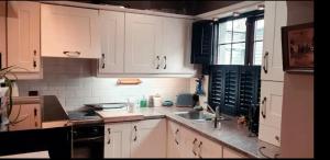 eine Küche mit weißen Schränken und einem Waschbecken in der Unterkunft Art Deco House Dublin Close to City Centre in Ballyfermot