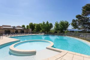 a large swimming pool with chairs around it at La Calade in L'Isle-sur-la-Sorgue
