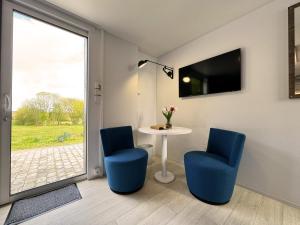 Habitación con 2 sillas azules, mesa y ventana en Golf Cubes Hohwacht en Hohwacht