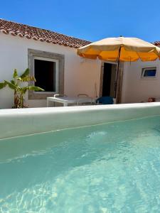 uma piscina com um guarda-sol ao lado de uma casa em Palmeirinha Guest House em Sintra