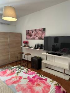 uma sala de estar com televisão e um tapete de flores em Casa Patrizia em Giardini Naxos