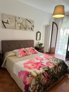una camera da letto con un letto con fiori rosa di Casa Patrizia a Giardini Naxos