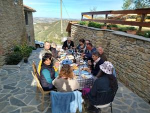 um grupo de pessoas sentadas em torno de uma longa mesa em Monte Cuccolo House B&B em Fontanelice