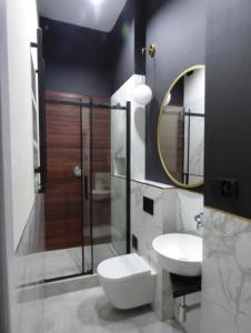 a bathroom with a toilet and a sink and a mirror at Kopernik Premium Rooms Apartment in Toruń