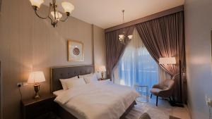 een slaapkamer met een bed, een stoel en een raam bij HOOUD Apartments in Khor Fakkan