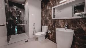 a bathroom with a toilet and a shower and a sink at HOOUD Apartments in Khor Fakkan
