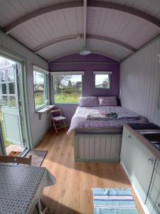 a bedroom with a bed and a table and windows at Market Street Shepherd's Hut Leitrim in Drumahayre