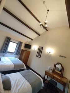 1 dormitorio con 2 camas y espejo en Ye Olde Bowling Green Inn en Bradwell