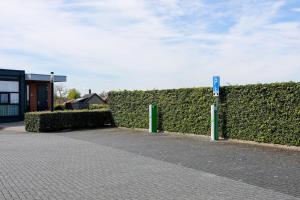 a hedge fence with a sign in front of a building at Strand Appartementen Wemeldinge I Bella Zeelandia in Wemeldinge