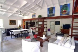 a living room with white furniture and a dining room at La Source Guest House in Orient Bay