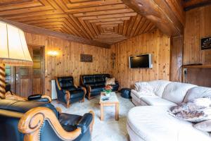 a living room with a couch and chairs and a tv at Chalet des Ormes - Maison pour 12 vue montage in Les Combes