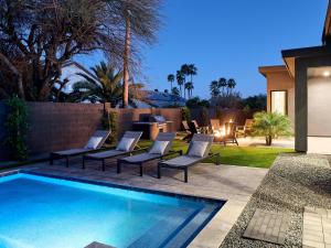 a backyard with a swimming pool and lounge chairs next to a fence at LUXE - Tulum House - New Build - Heated Pool in Scottsdale