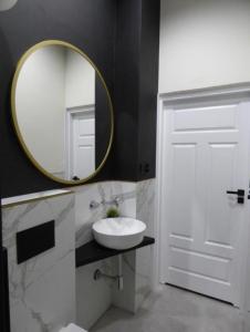 a bathroom with a sink and a mirror at Kopernik Premium Rooms Apartment in Toruń